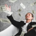 Investor sitting down, throwing paper money into the air.